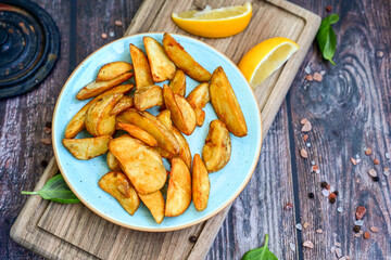  Home made Wedges spicy Potatoes and fresh  lemon on wooden background