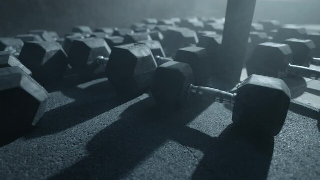 equipment for powerlifting and bodybuilding in gym, heavy dumbbells on floor in dark sport club