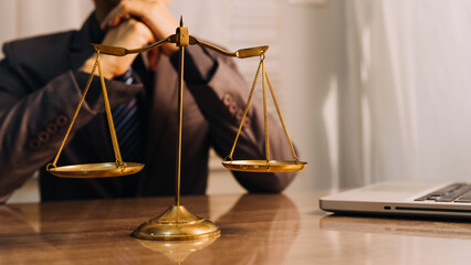 Justice and law concept.Male judge in a courtroom with the gavel, working with, computer and docking keyboard, eyeglasses, on table in morning light