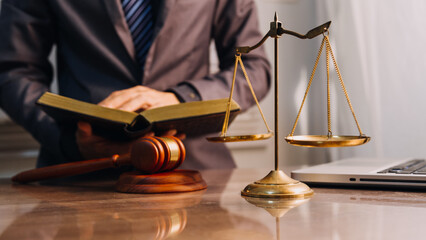 Justice and law concept.Male judge in a courtroom with the gavel, working with, computer and docking keyboard, eyeglasses, on table in morning light