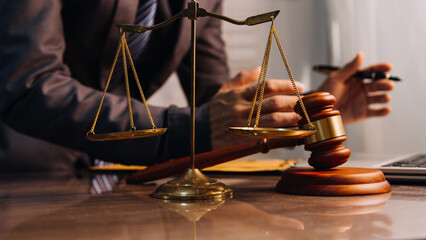 Justice and law concept.Male judge in a courtroom with the gavel, working with, computer and docking keyboard, eyeglasses, on table in morning light