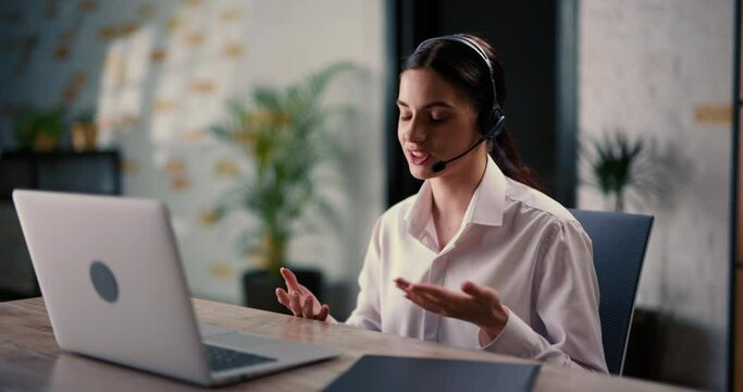 Woman with smile on face gives speech to her colleagues at informal online meeting. Caucasian millennial woman communicates via online video link and gesticulates while discussing work with colleagues
