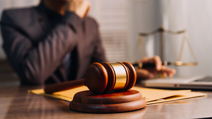 Justice and law concept.Male judge in a courtroom with the gavel, working with, computer and docking keyboard, eyeglasses, on table in morning light