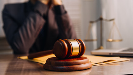 Obraz premium Justice and law concept.Male judge in a courtroom with the gavel, working with, computer and docking keyboard, eyeglasses, on table in morning light