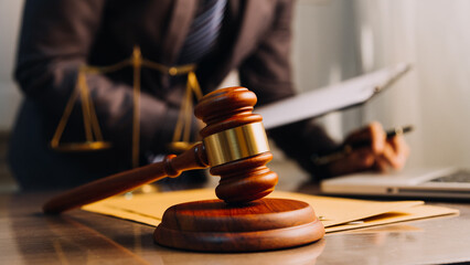 Justice and law concept.Male judge in a courtroom with the gavel, working with, computer and docking keyboard, eyeglasses, on table in morning light