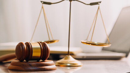 Justice and law concept.Male judge in a courtroom with the gavel, working with, computer and docking keyboard, eyeglasses, on table in morning light