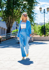 Full length portrait of a business lady in a blue suit walking in the street