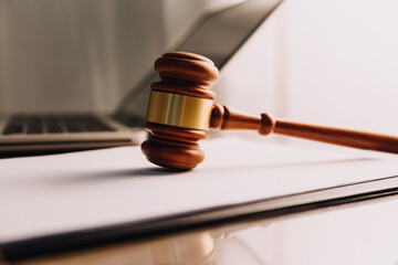 Obraz premium Justice and law concept.Male judge in a courtroom with the gavel, working with, computer and docking keyboard, eyeglasses, on table in morning light