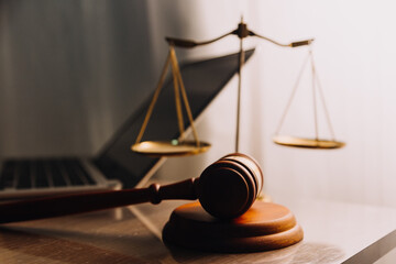 Justice and law concept.Male judge in a courtroom with the gavel, working with, computer and docking keyboard, eyeglasses, on table in morning light