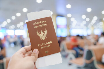 Hand holding Thailand passport and boarding pass ticket in International airport. Travel, vacation and transportation concepts