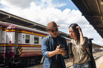 Couple Asian depressed mistakes a train. Two backpacker Traveler waiting at train station. Boarding the wrong ticket feeling stressed. Planning Fail trip tourist missing