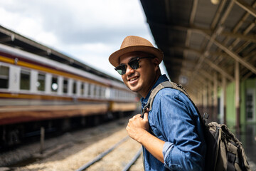 Freedom traveler young asian man at terminal train station. Happy tourist travel by train on...