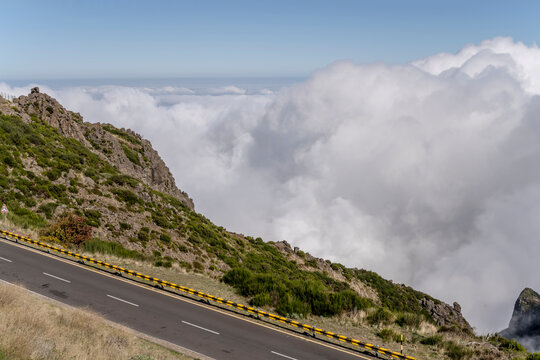 panoramic road with barrier on slope above the clouds at Miradouro de Areeiro peak, Madeira