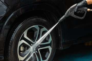 Fototapeta premium Man worker washing car service. Car wash cleaning station high pressure water. Employees clean a vehicle professionally.