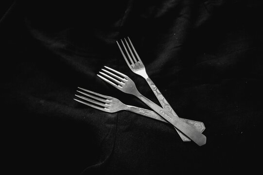 Silver forks on the black cloth
