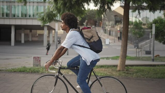 Happy young stylish African American man going to work by bicycle - Sustainable transport inn the city 