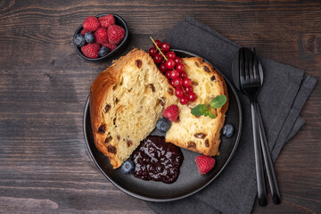Italian Christmas or Easter fruitcake panettone with raisins, candied, berries and berry jam