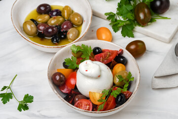 burrata cheese salad with tomatoes, olives and olive oi
