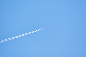 Plane flying through a clear blue sky leaving a long trail behind