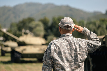 Asian man special forces soldier saluting standing against on the field Mission. Commander Army soldier military defender of the nation in uniform standing near battle tank while state of war.