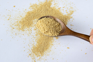 Non-enriched dry food yeast in a wooden spoon on a white background. Healthy nutrition, a supplement to food.