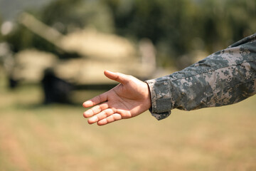 Asian man special forces soldier standing against on the field Mission Giving hand make peace. Commander Army soldier military defender of the nation in uniform near battle tank while state of war.
