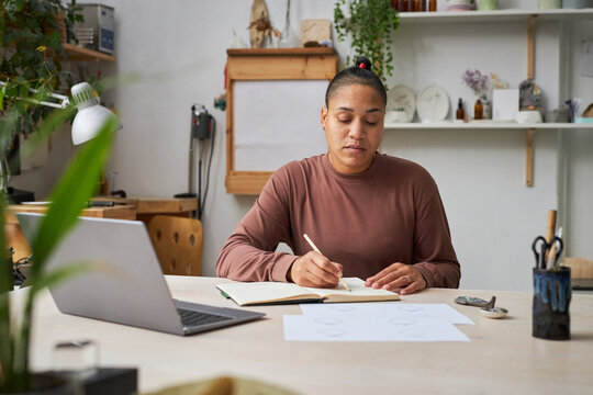 Portrait of multiethnic female artist working on new designs in studio