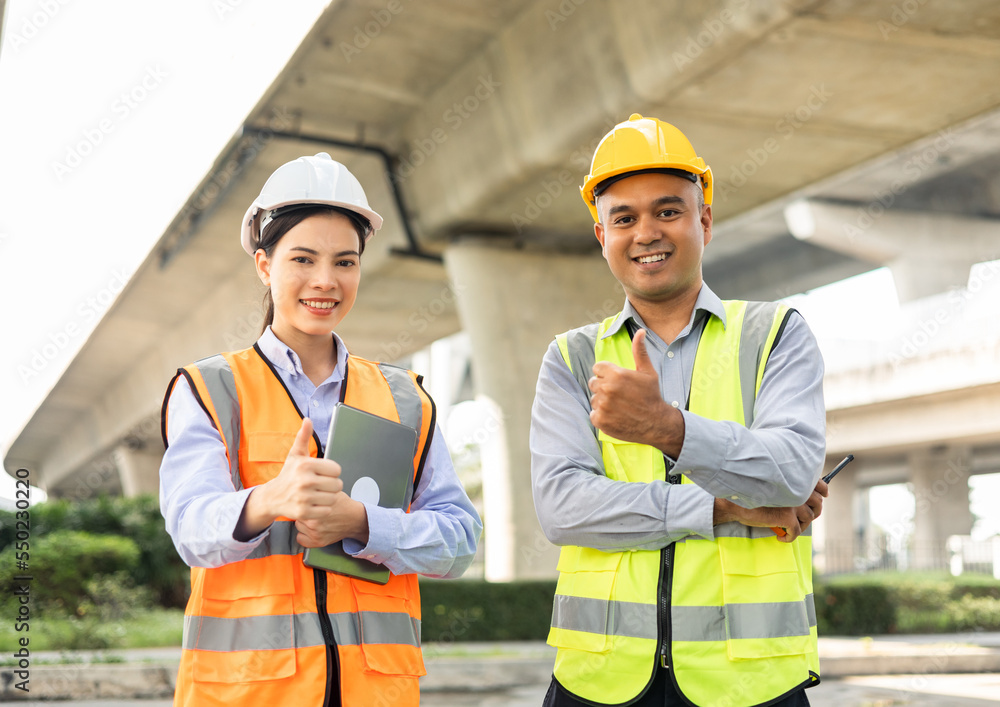 Wall mural two asian worker engineer man and woman architect looking construction with white safety helmet in c