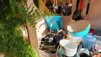 A mess in the kitchen. Dirty dishes around the sink. The concept of advertising cleaning service, displaying the routine after the party, holiday.