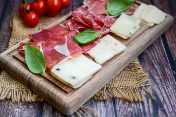 Slices Of  Traditional Italian antipasti mortadella Bolognese,salame Milano, parmesan cheese  and prosciutto crudo   on a wooden  cutting board.