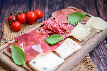 Slices Of  Traditional Italian antipasti mortadella Bolognese,salame Milano, parmesan cheese  and prosciutto crudo   on a wooden  cutting board.