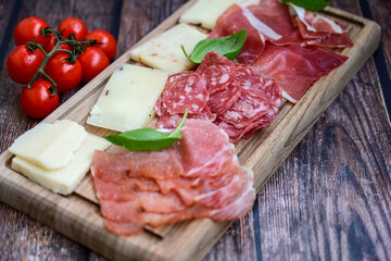 Slices Of  Traditional Italian antipasti mortadella Bolognese,salame Milano, parmesan cheese  and prosciutto crudo   on a wooden  cutting board.
