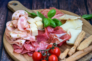Slices Of  Traditional Italian antipasti mortadella Bolognese,salame Milano, parmesan cheese  and prosciutto crudo   on a wooden  cutting board.