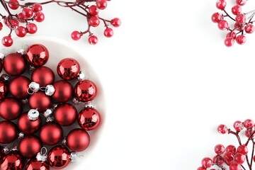 Red Christmas balls and berries are on the table and on the plate.