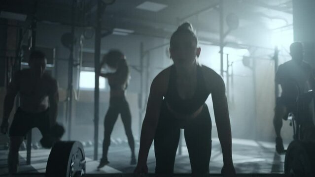 deadlift in old gym, beautiful sportive woman lifting barbell in dark fitness club, epic endurance