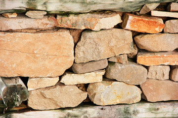 the texture of a stone wall made of brown stones and old moldy wood