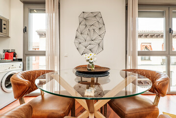 Living room with circular glass dining table surrounded by brown leather upholstered armchairs
