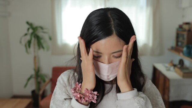 Asian young woman put a mask on. She is tired of it. Dolly in.