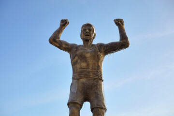 A sculpture of an athlete covered with ice against a blue sky.