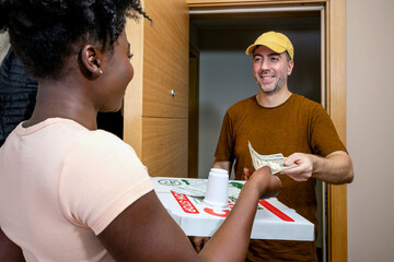 A young woman is paying for pizza delivery. Girl handing cash to a pizza delivery guy. Focus on hands and money.
