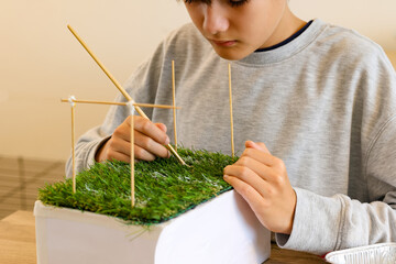 Boy workshop school project create soccer field with artificial grass on school assignment creative handcraft from a carton board,  Creative hobby making handcraft toy football field for world's cup.