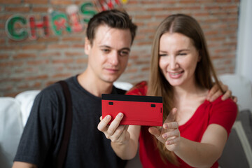 Happy couple taking selfie with smartphone sitting on sofa in living room at home,Celebrating New Year together.