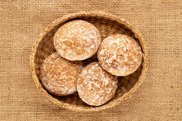 Several sweet tasty gingerbread cookies in a straw plate on a jute cloth, macro, top view.