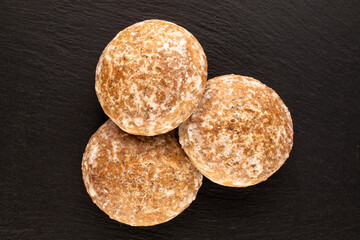 Three sweet tasty gingerbread cookies on slate stone, macro, top view.