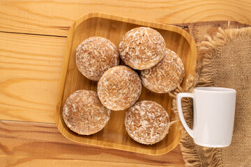 Several sweet delicious gingerbread cookies with bamboo plate and white cup on wooden table, macro, top view.