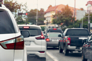 Rear side of white cars on the asphalt road heading towards the goal of the trip. Traveling for work during rush hour. Environment blurred of other cars during the day. with town and trees.