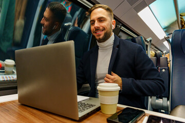 Business man commuting by train and working on his laptop, he's using his air pods for his video call meeting
