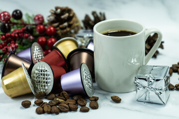 Coffee capsules next to a cup of hot coffee and on a white table against the background of...
