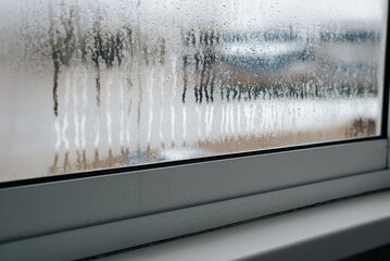 Wet misted window indoors, thaw. Side view, close-up, selective focus