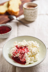 Homemade ricotta soft cheese or cottage cheese served with raspberry jam and fresh bread and cup of cocoa on linen tablecloth. Healthy cozy breakfast. Selective focus - 550245898